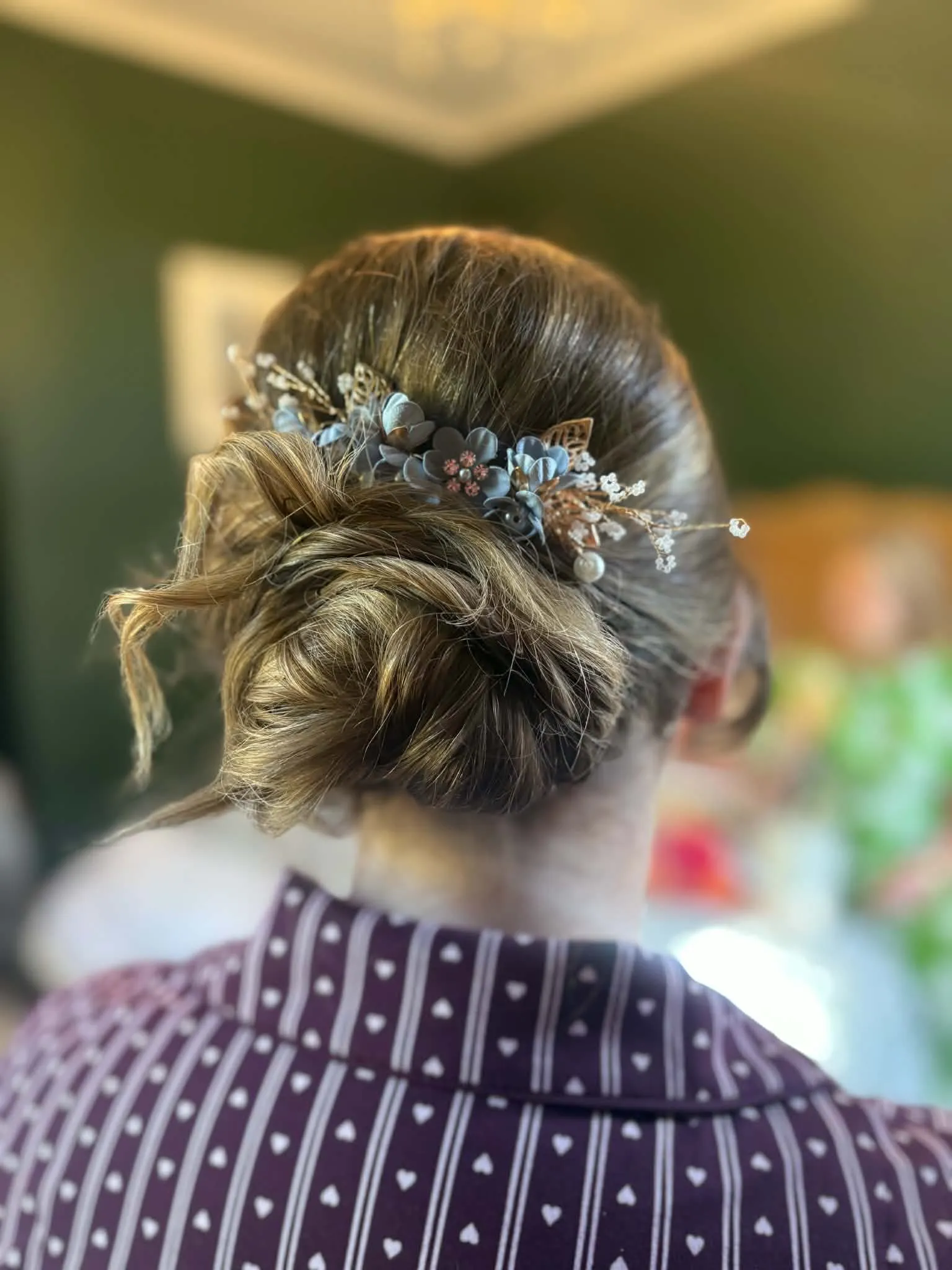 Loose textured updo in fair hair with a dusky blue flower and pearl hair vine